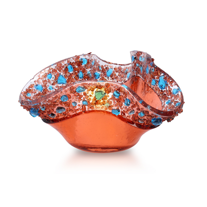 Salmon colored glass votive with blue specks dancing around the rim