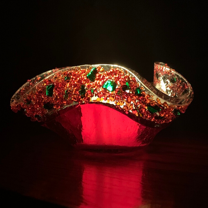 Illuminated Red Christmas Art Glass Votive with green specks of glass along the rim